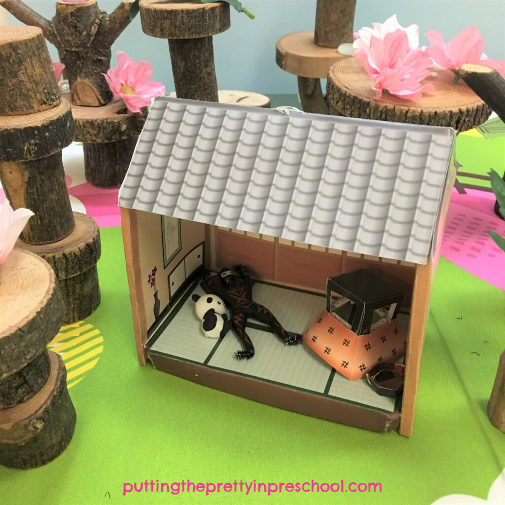 Cherry blossom tree book-inspired small world with pink flowers, gems, and panda and ninja figurines.