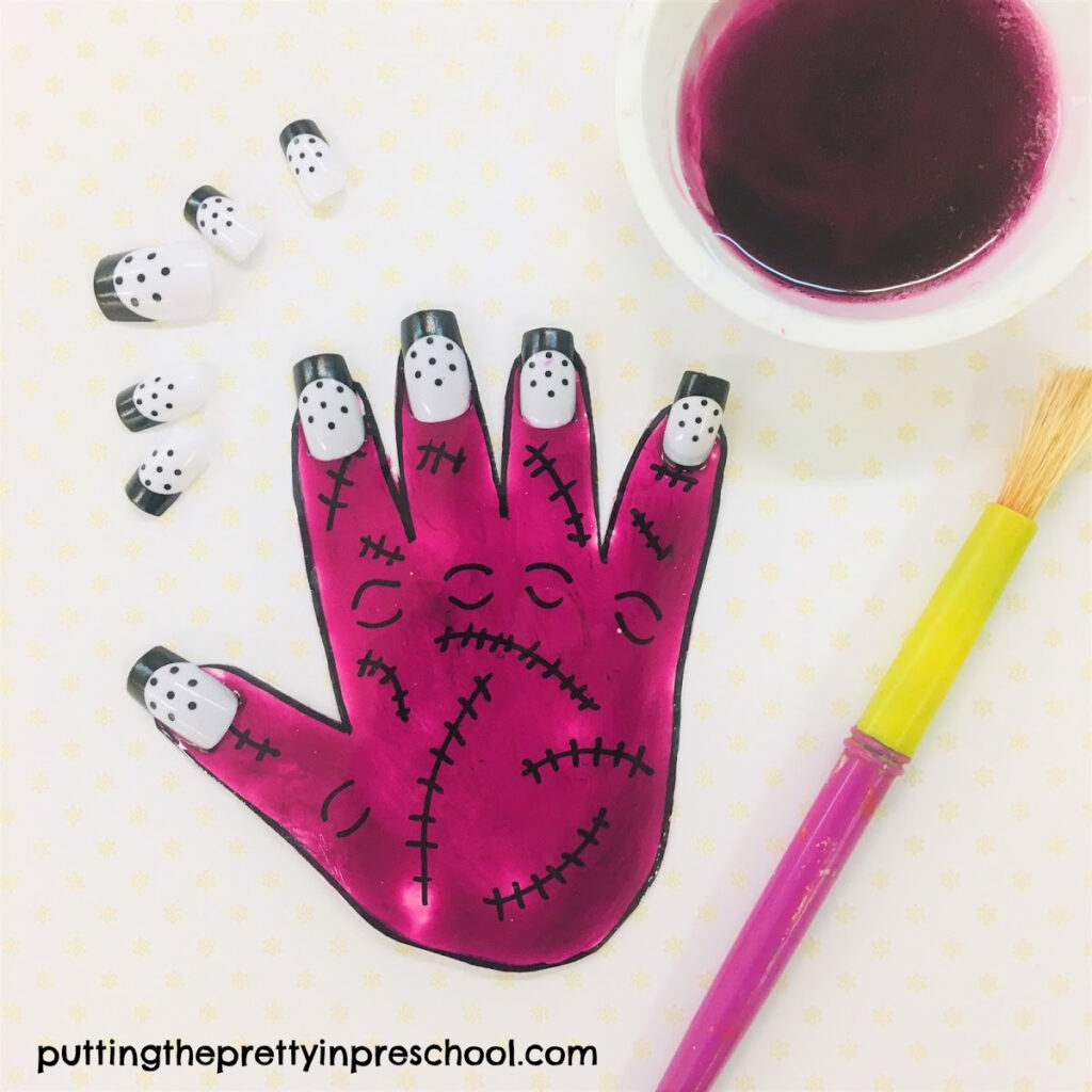 Purple painted hand with stitches drawn on and polka dot nails.