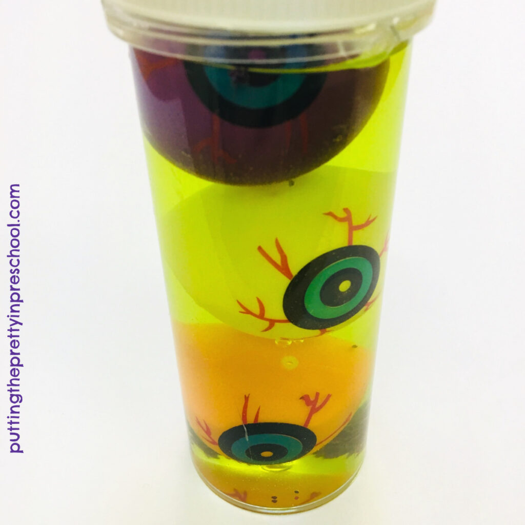 Plastic eyeballs and neon yellow water in a sensory tube.