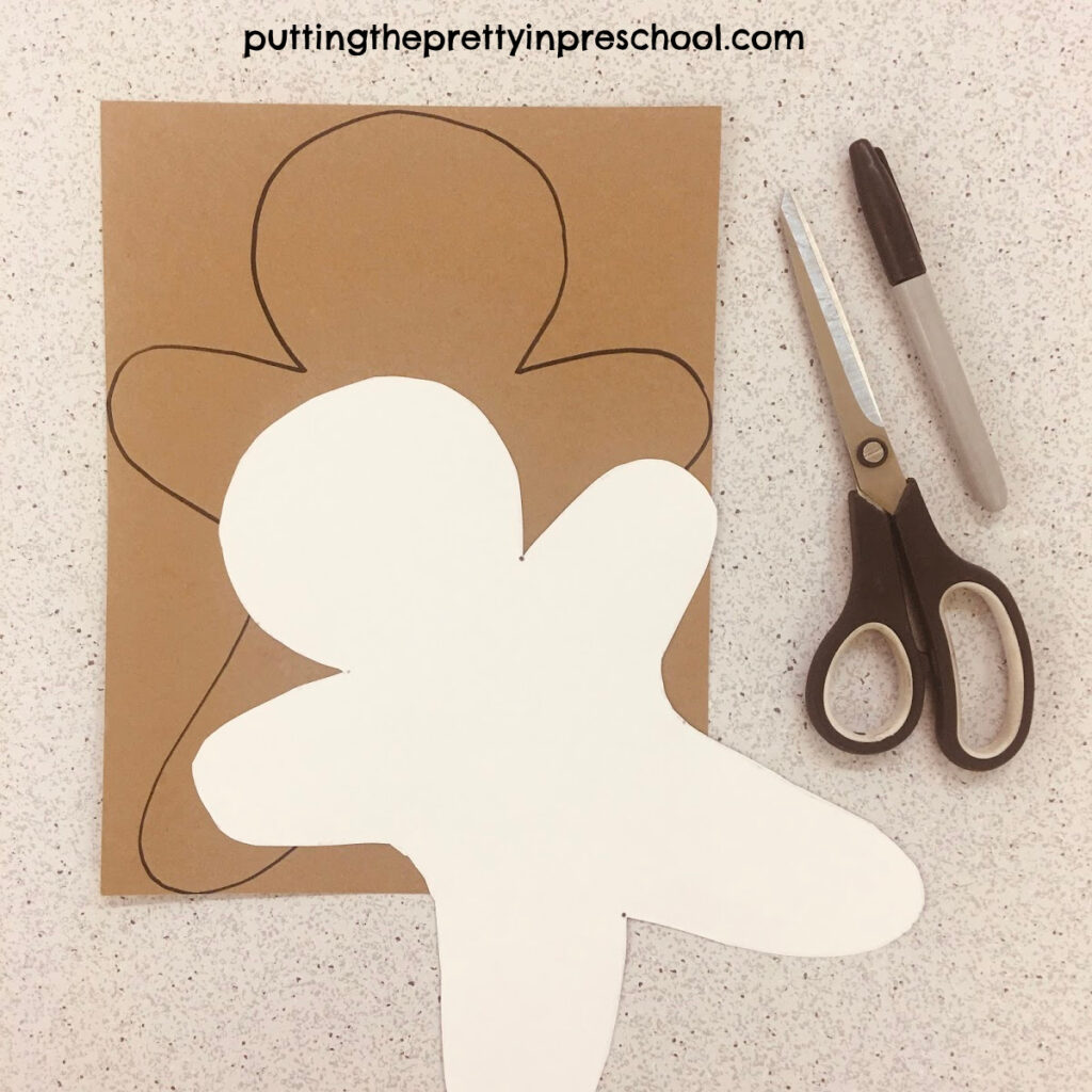 Gingerbread man template traced onto kraft cardstock paper, ready to be cut out.