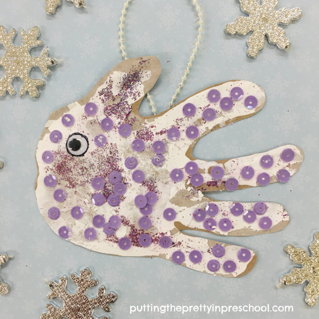 Handprint fish ornament embellished with sequins, glitter, and a wiggly eye.
