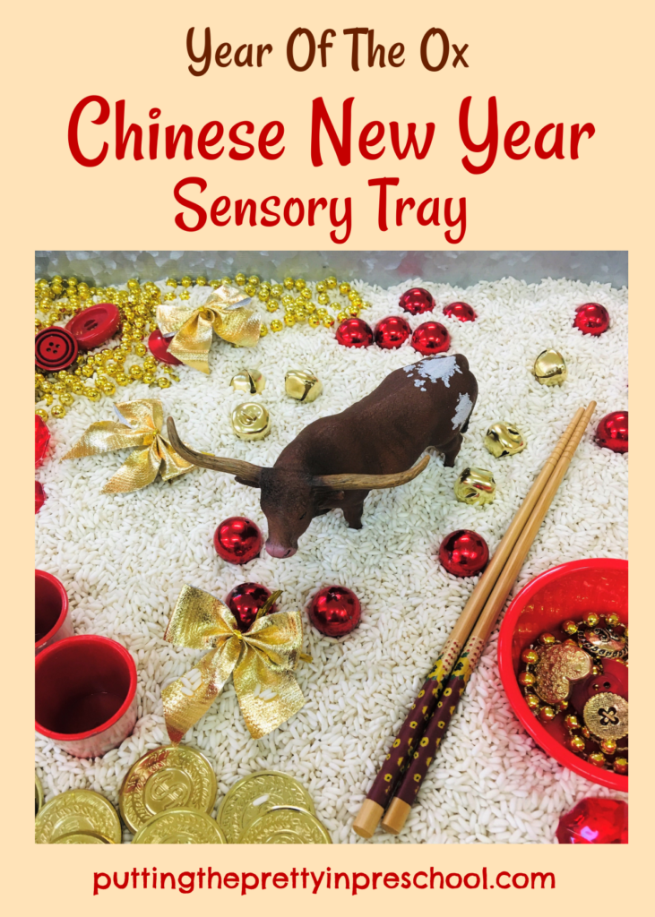 Year of the Ox Chinese New Year rice-based sensory tray with a bull figurine and red and gold loose parts.