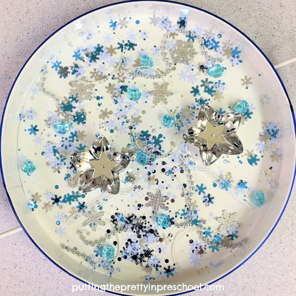 Shiny pieces rule in this snowflake confetti based winter sensory tray.