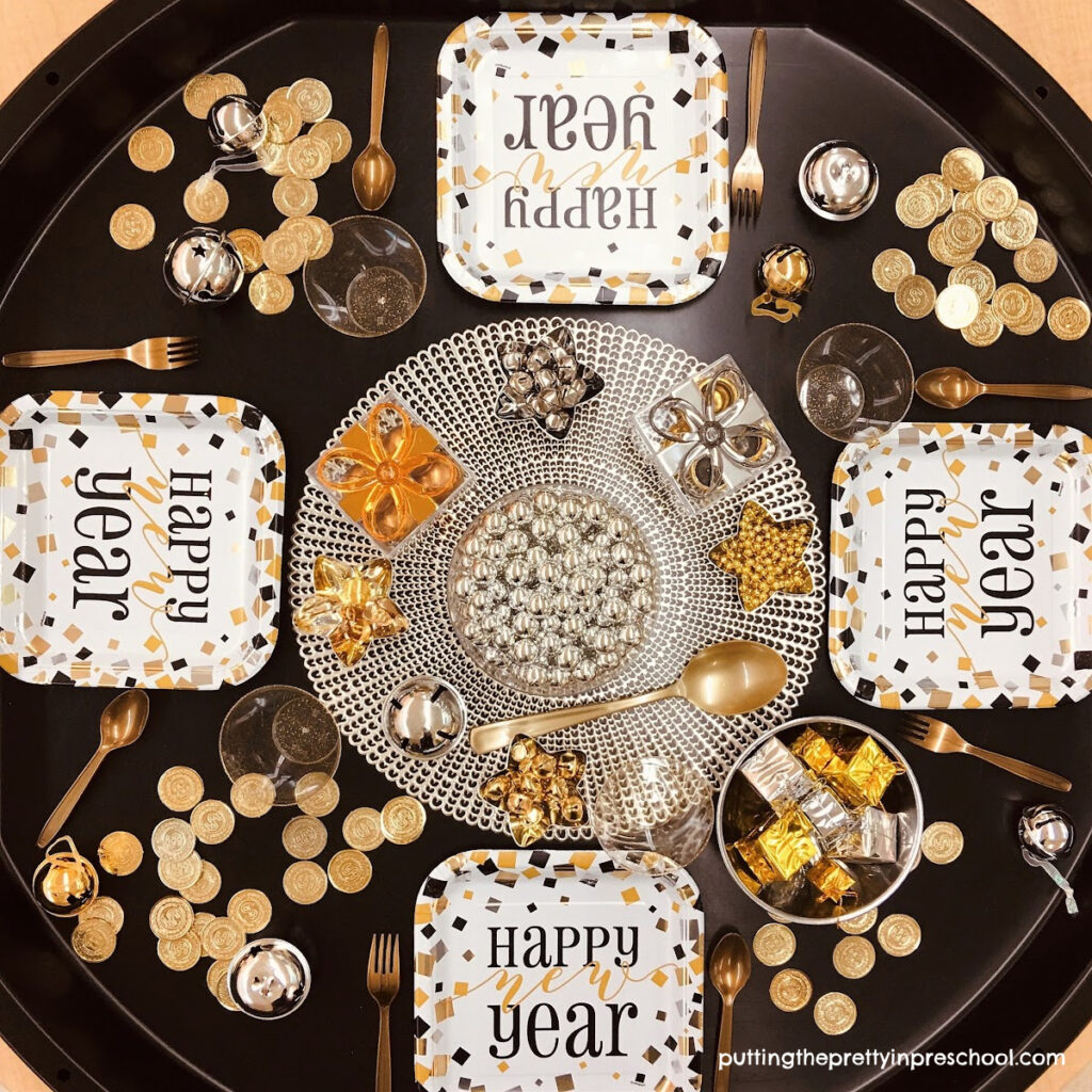 New Year's Eve tuff tray filled with dinner-themed loose parts little learners will love to party with.