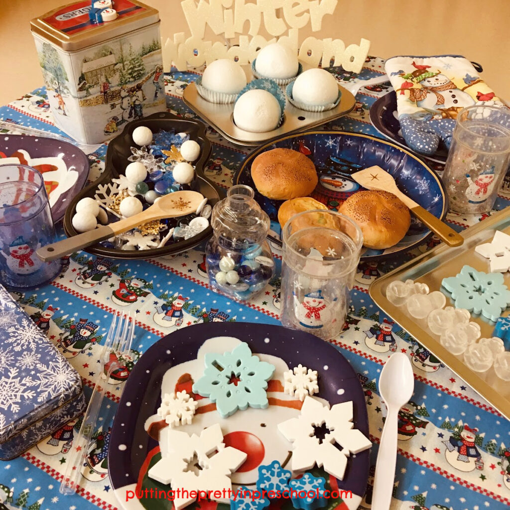 A sparkly, kids' Winter Wonderland play tablescape with snowman, snowflake, and snowball decor for little learners to explore.