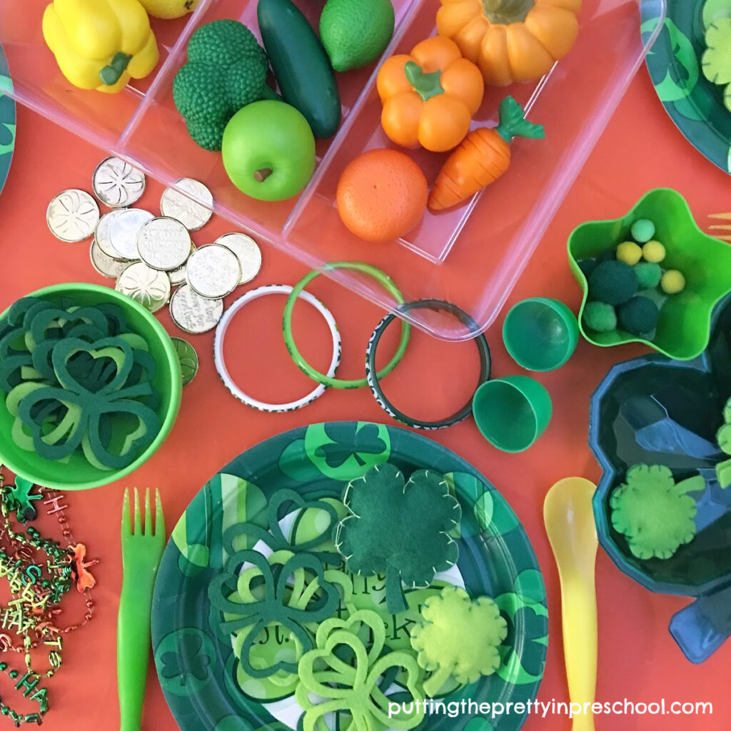 Set up this cheery St. Patrick's Day tablescape that is filled with green, yellow, and orange loose parts and plenty of shamrocks.