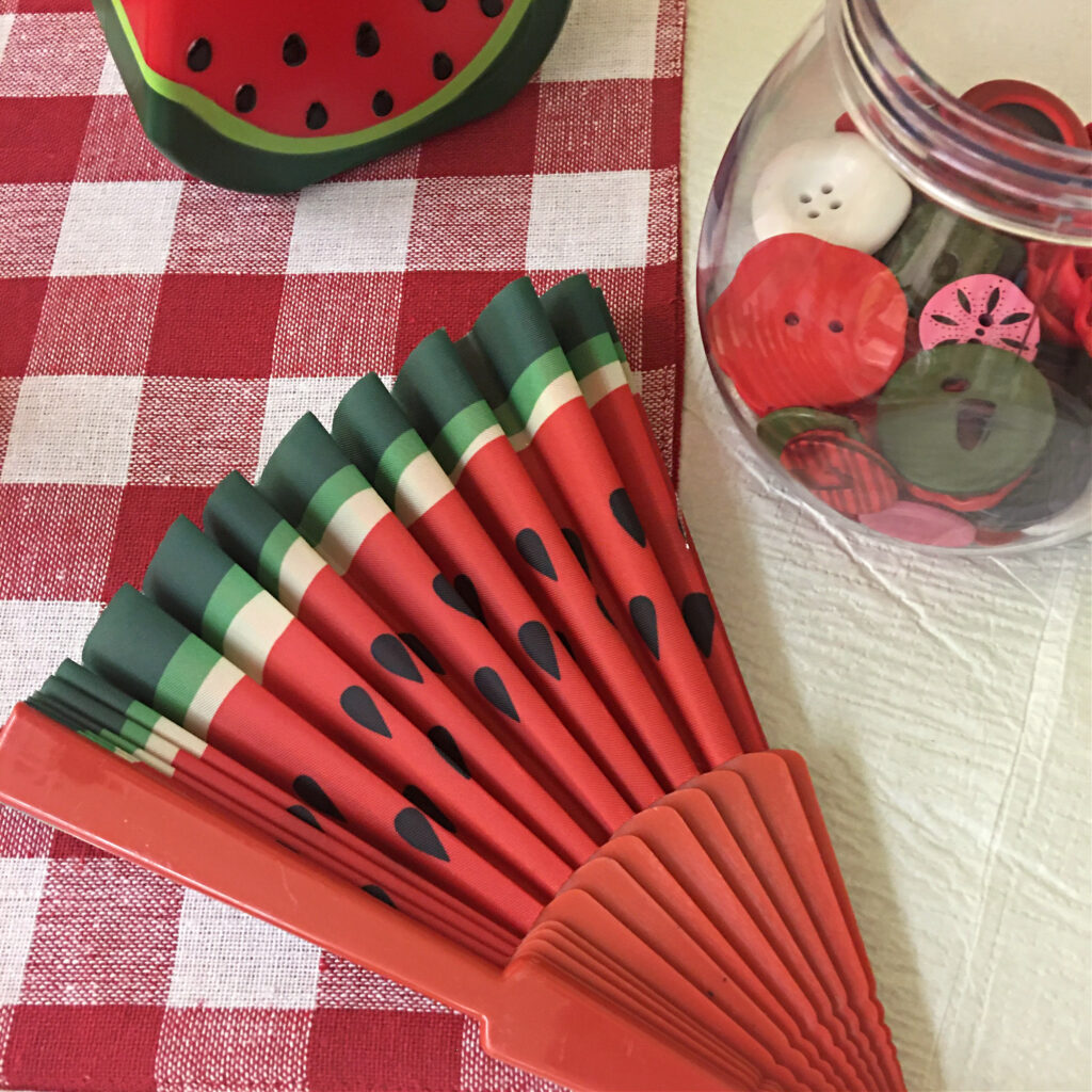 A themed fan and button loose parts add interest and play possibilities to a watermelon dramatic play center.