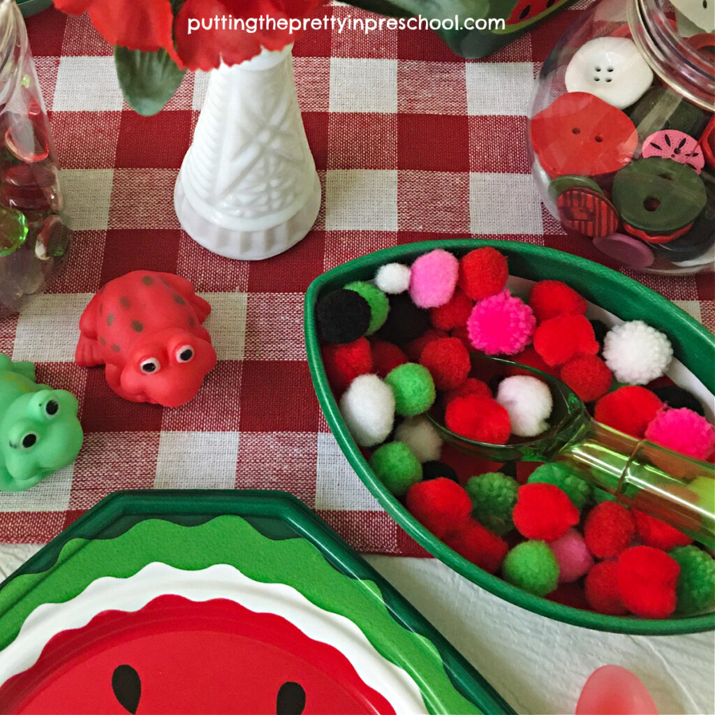 Pompoms in red, pink, green, white, and black add interest and play possibilities to a watermelon dramatic play center.